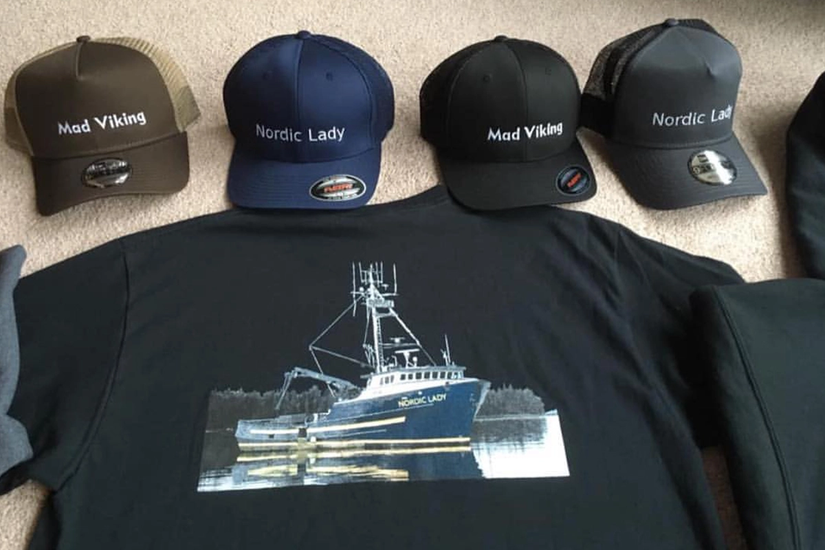 Embroidered trucker hats and a printed T-shirt featuring fishing vessel designs and names “Mad Viking” and “Nordic Lady.”