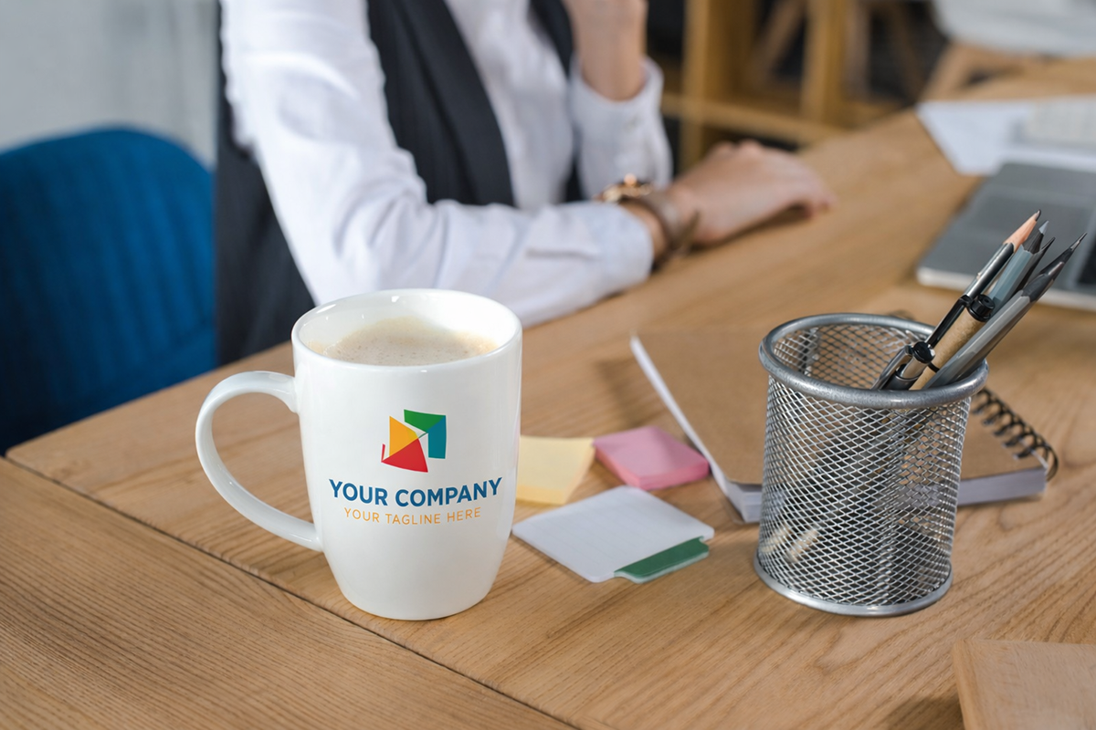 Branded coffee mug on an office desk beside stationery, representing custom mugs for corporate branding and office use.