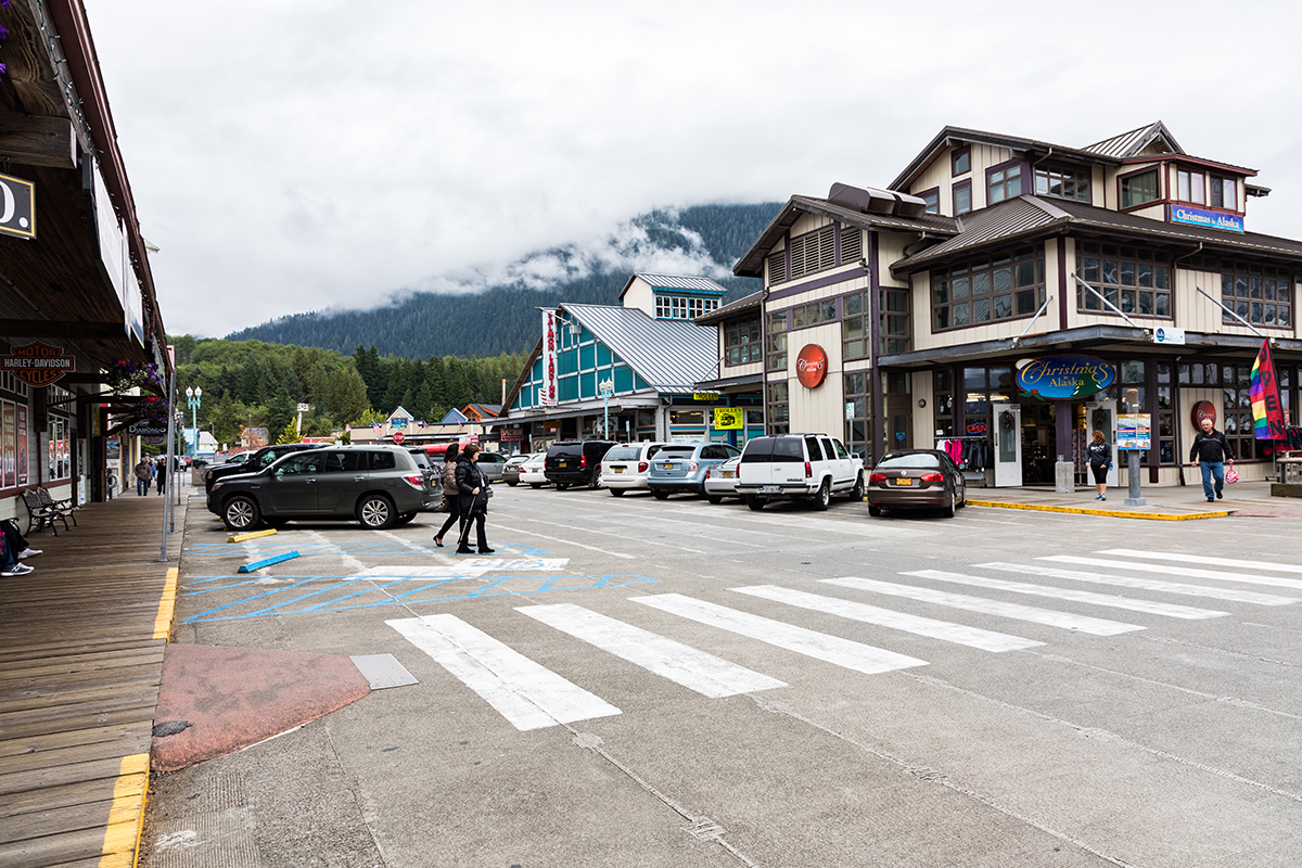 Downtown Ketchikan Alaska street view with shops, parked cars, and pedestrians on cloudy day