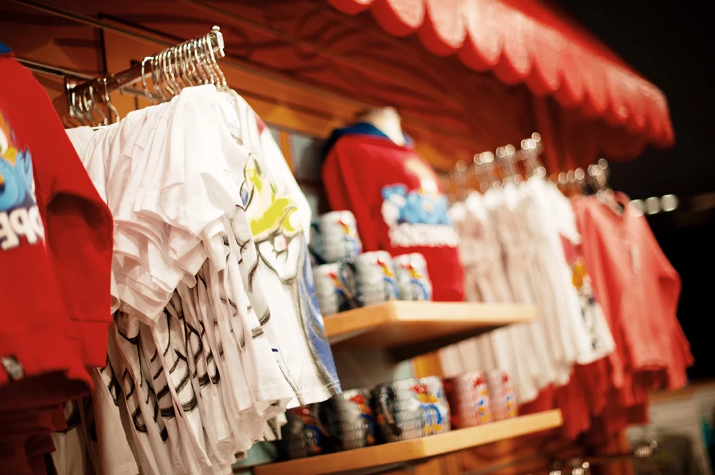 Retail display of graphic t-shirts and souvenir mugs in a colorful gift shop