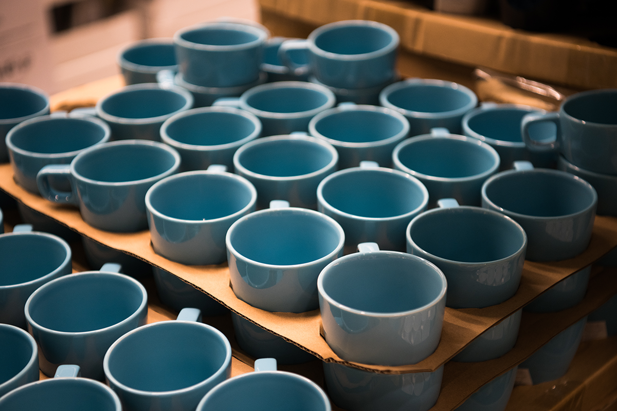 Stack of aqua blue ceramic coffee cups arranged on trays in cafe setting